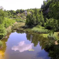 Malowniczy widok na jezioro szmaragdowe w Kielcach, otoczone bujną zielenią i skalistymi zboczami.