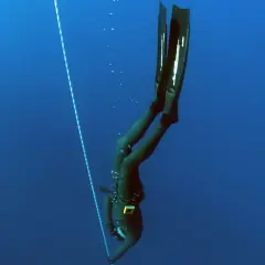 Nurkini w piance, z płetwami, opada w głębiny, zbliżając się do kolejnego freediving rekordu.