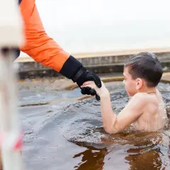 Chłopiec w lodowatej wodzie, trzymający się ręki dorosłego. To może być jego pierwszy raz, gdy doświadcza szok termiczny.
