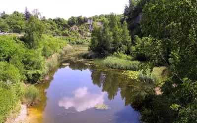Malowniczy widok na jezioro szmaragdowe w Kielcach, otoczone bujną zielenią i skalistymi zboczami.