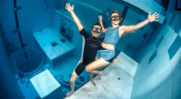 Para, która cieszy się freedivingiem, czyli nurkowaniem na wstrzymanym oddechu, w basenie głębinowym.