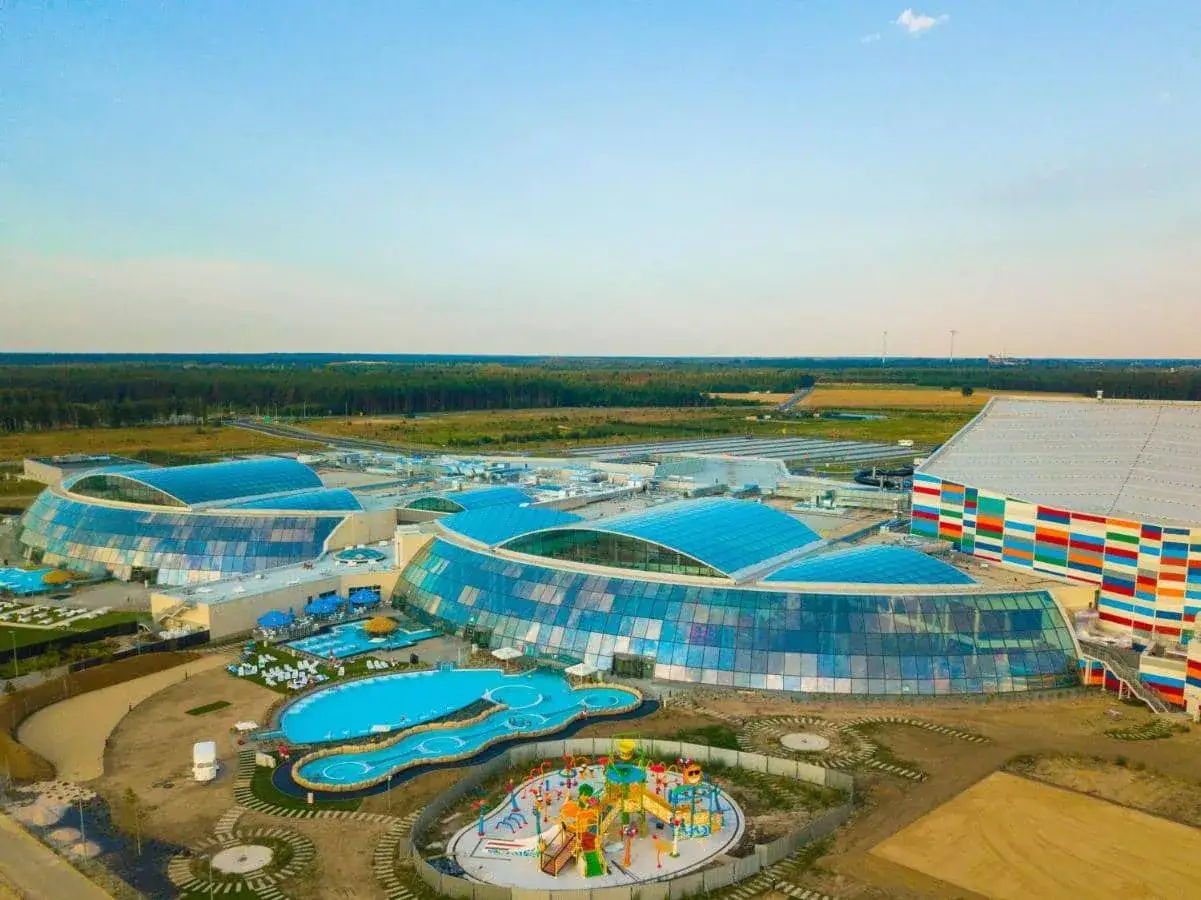 Nowoczesny kompleks z basenami i zjeżdżalniami, największy park wodny w Polsce, otoczony zielenią.