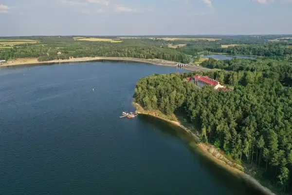 Zalew Chańcza otoczony lasem, z hotelem i pomostem.